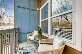 a balcony with two chairs and a table and a large window